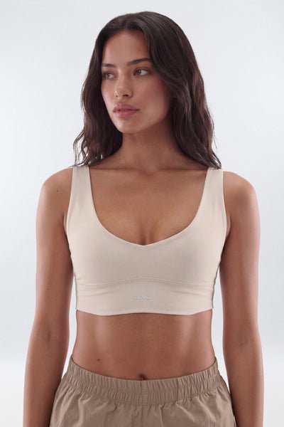 Woman wearing a beige sports bra and pants on a white background