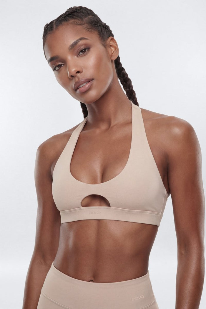 Woman wearing a beige sports bra and leggings on a white background