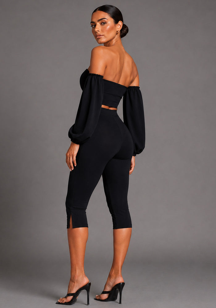 Side back image of a model wearing the VSPR Belle Sweetheart Neckline Puff Sleeve Black Top highlighting the structured puff sleeves, smooth stretch fabric, and flattering body-hugging shape, standing against a grey studio backdrop.