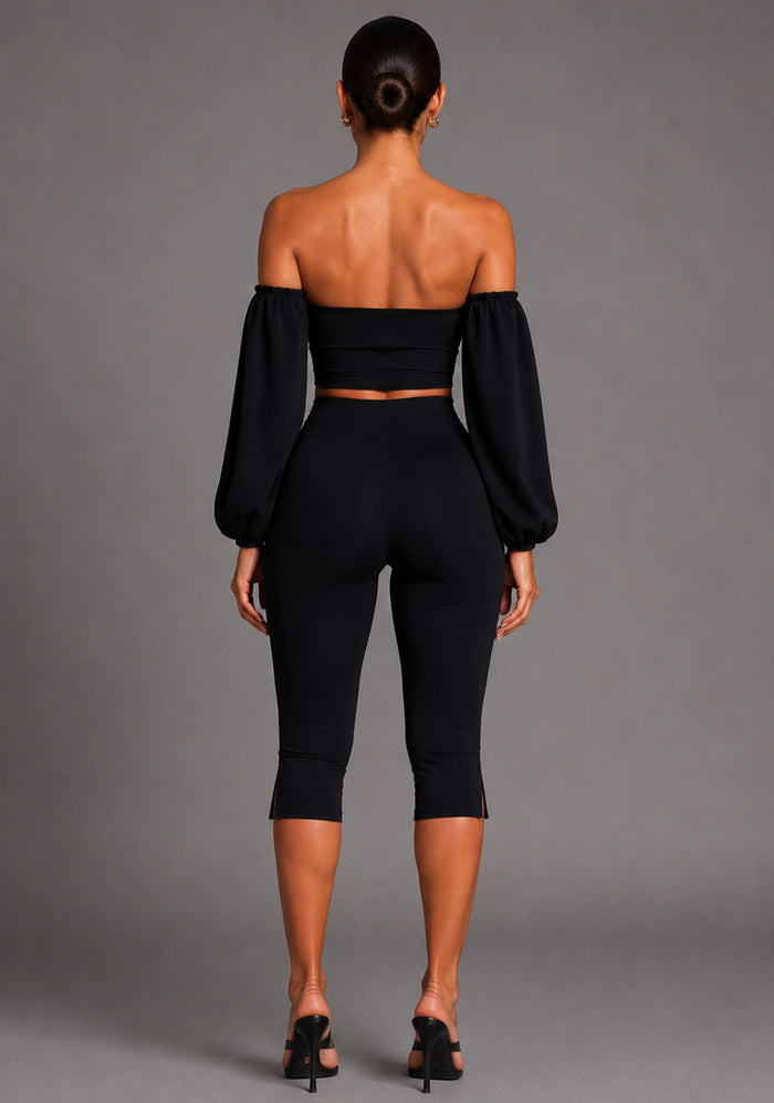 Back image of a model wearing the VSPR Belle Sweetheart Neckline Puff Sleeve Black Top featuring dramatic sleeve detailing, a sleek fitted design, and a polished silhouette, posed against a grey studio backdrop.
