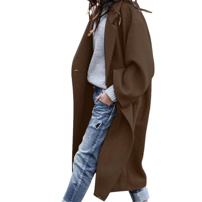 Person wearing a brown coat over a light blue sweater and jeans on a white background