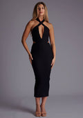 Front image of a model wearing the Vesper Dalton Cross Neckline Midaxi Dress in Black featuring a modern criss-cross neckline, subtle cut-outs, and a sleek bodycon silhouette against a grey studio backdrop.