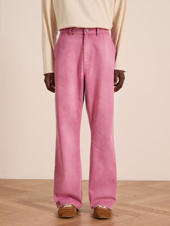 Person wearing FOUND Flare Work Pants in pink, a cream long-sleeve shirt, and brown suede shoes, standing on a wooden floor against a plain light background.