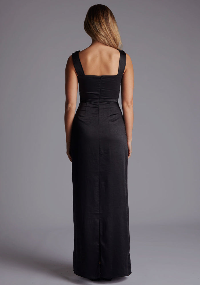Back image of a model wearing the Vesper Jodie Cowl Neck Satin Maxi Dress in Black featuring a clean silhouette, invisible zip, and subtle skirt split.