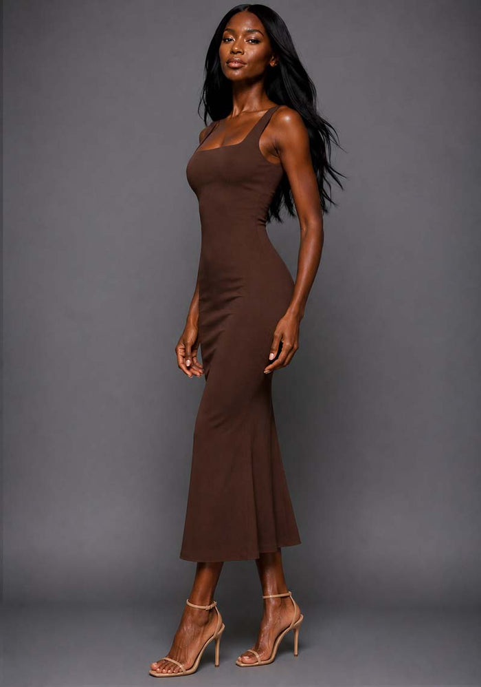 Side front image of a model wearing the VSPR Marianna Chocolate Brown Midaxi Dress showcasing the figure-enhancing silhouette, wide straps and elegant fishtail shape against a grey studio backdrop.