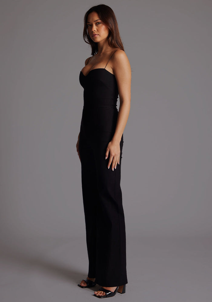 Side front image of a model wearing the VSPR Rogan Sweetheart Neck Wide Leg Jumpsuit in Black, highlighting the smooth bodice fit and flowing wide-leg design from an angled perspective.