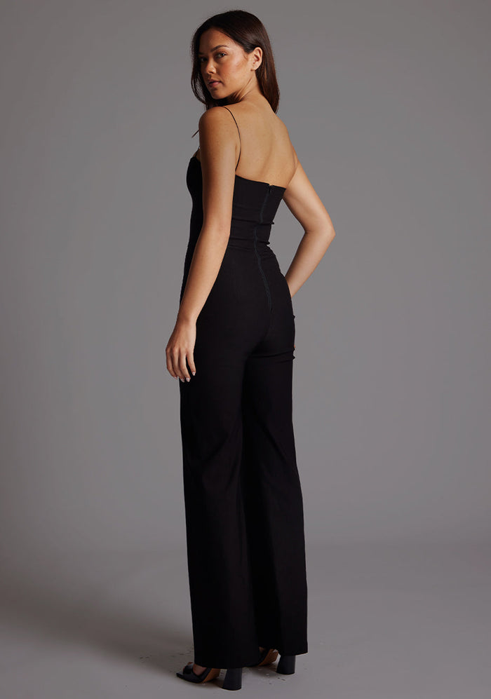 Side back image of a model wearing the VSPR Rogan Sweetheart Neck Wide Leg Jumpsuit in Black, revealing the clean back lines and elegant flow of the wide-leg pants.
