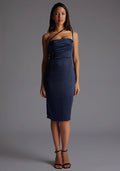 Front image of a model wearing a navy satin midi dress with a straight neckline with a asymmetric strap across front of chest and invisible centre back zip. The design featured is the Vesper Rosalina Navy Satin Midi Dress