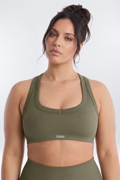 Woman wearing an olive green sports bra and leggings on a white background