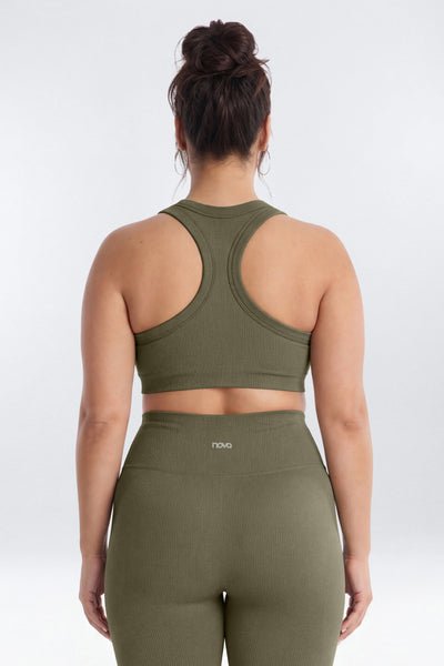 A woman viewed from the back wearing an olive green sports bra and matching high-waisted leggings.