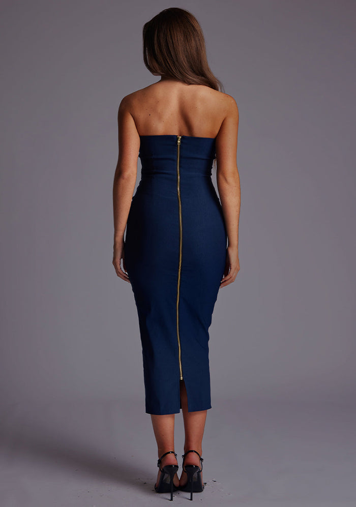 Back image of a model wearing a navy midaxi dress, featuring a strapless neckline with gold zip at the back. The design featured is the Vesper Shelbie Navy Strapless Midaxi Dress.