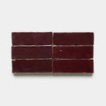 Six rectangular Sumac 2x6 tiles by Zia Tile, glossy and dark maroon, are arranged in two rows of three against a plain white background.