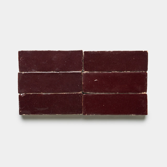 Six rectangular Sumac 2x6 tiles by Zia Tile, glossy and dark maroon, are arranged in two rows of three against a plain white background.