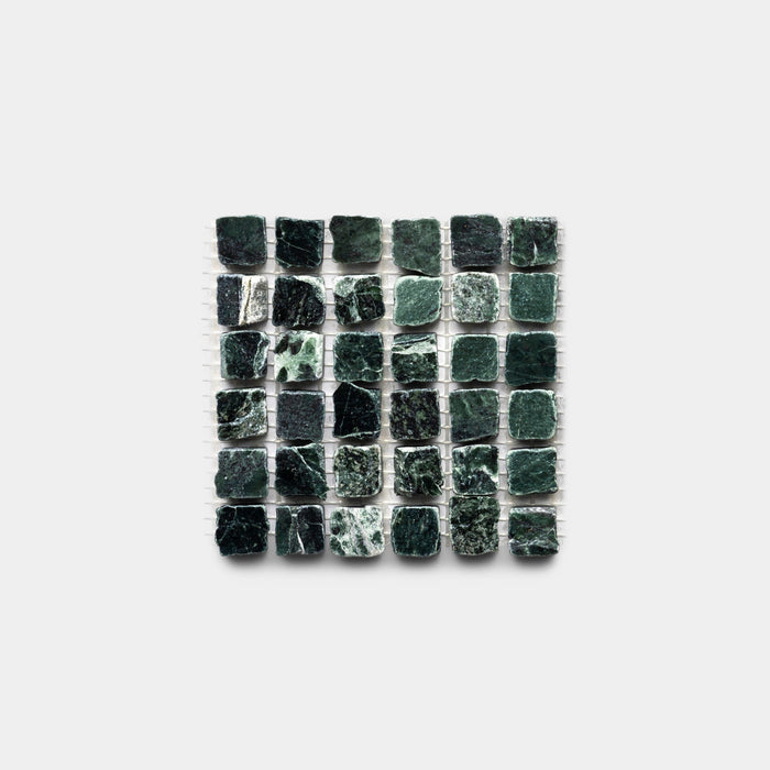 A square grid of Zia Tile’s Verde Alpi 5/8 sample—small, dark green stone tiles with textured surfaces and unique marbling—creates a varied, natural pattern against a white background.